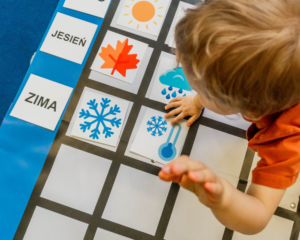 Chłopiec układa elementy: pory roku na macie edukacyjnej SPE