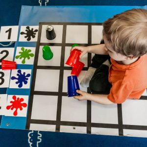 Chłopiec układa elementy i kubeczki na czteroczęściowej macie edukacyjnej SPE KodujMata